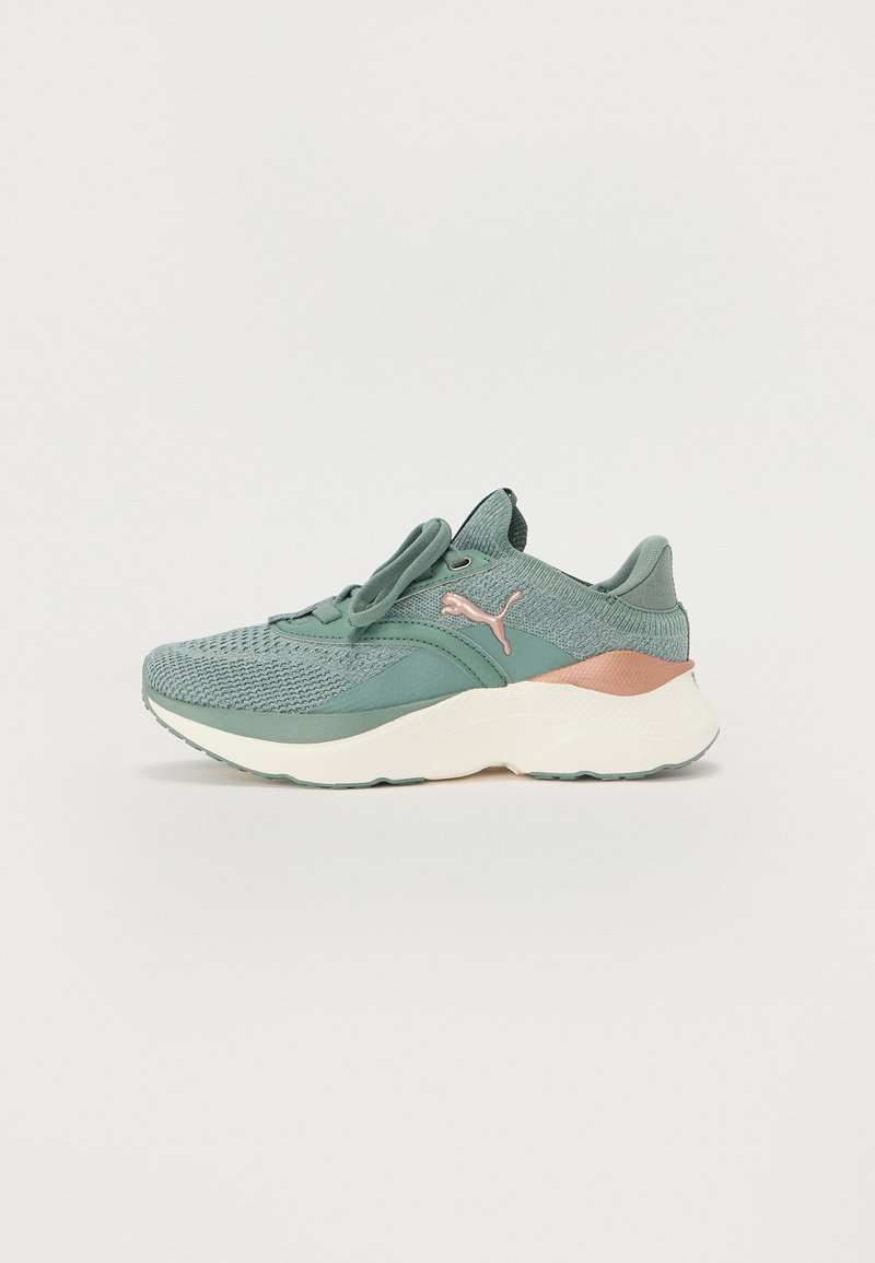 Scarpa sportiva verde chiaro con una parte superiore texturizzata, caratterizzata da un accento rosa sul tallone e una suola bianca. Design con lacci, suola intermedia imbottita.