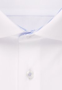 Krave på en hvid skjorte med blå kant og en gennemsigtig knap fastgjort i midten øverst.