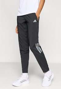 Μαύροι αθλητικοί παντελόνες με κωνικό σχέδιο, ελαστική μέση και πλαϊνές τσέπες. Διακριτικές τρεις ρίγες σε ανακλαστικό γκρι χρώμα στα κάτω μέρη των ποδιών.