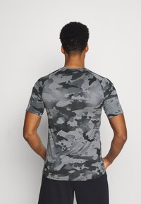 Kortärmad träningsskjorta i grå camouflage-mönster, med ett mjukt och stretchigt material, rund halsringning och platta sömmar.