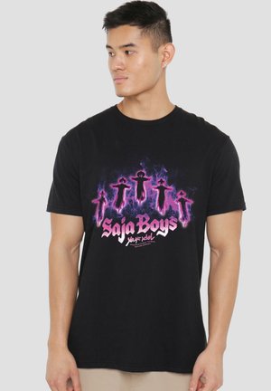 Young man wearing black t-shirt with glowing pink and purple humanoid figures and text "Saja Boys" looking sideways.