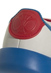 Witte sneaker met een rode en blauwe rubberen hak. Beschikt over een rood Spiderman-logo en blauwe stoffen accenten. Glad materiaal met textuurcontrast.
