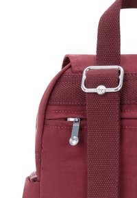 Vinröd ryggsäck med texturerad tyg, silverdetaljer, justerbar axelrem och en ficka med dragkedja framtill med en stjärnformad drag.