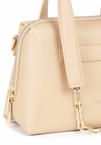 Borsa a mano in pelle beige con forma strutturata, dotata di chiusura con zip, accessori in tonalità oro e tracolla a catena rimovibile.