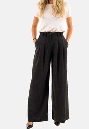 Pantalones negros de pierna ancha con pliegues, cintura alta y bolsillos laterales. Combinados con una camiseta rosa clara y tacones negros.
