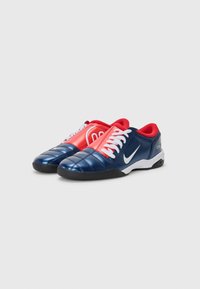 Navy and red athletic shoes with a glossy finish, featuring a quilted design, white laces, and a black sole with Nike branding.