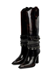 Botas negras de tacón alto hasta la rodilla con punteras puntiagudas, tapas metálicas en los dedos y múltiples correas decorativas y cadenas alrededor del área del tobillo.