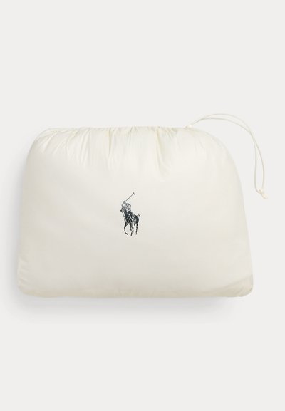 Kreemika värviga paelaga kotike, kus on Polo Ralph Laureni logo, millel on joonistus mustas ratsutavast polomängijast.