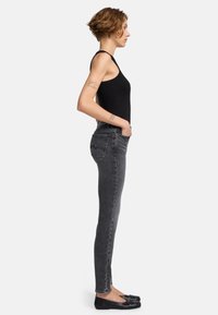 Skinny jeans van vervaagd zwarte denim, high-waisted met een strakke pasvorm. Draag het met een zwart tanktop en zwarte ballerina's, wat een minimalistisch ontwerp toont.