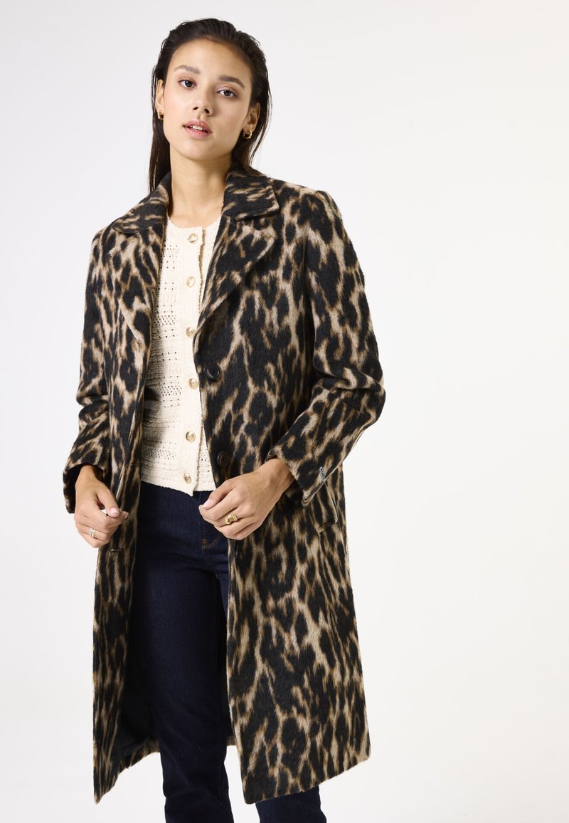 Leopardenprint wolwantenk met een geknipt kraag, enkelvoudige knoopsluiting en lange mouwen, gecombineerd met een lichte, gestructureerde top.