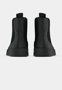 Sorte højtop sneakers med en glat gummisål, strækbare sider og bageste pull-tabs for nem påtagning. Teksturerede materiale accenter på siderne.