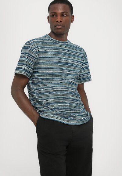 T-shirt rayé dans des tons de bleu avec des lignes horizontales, col rond, manches courtes et coupe décontractée, associé à un pantalon noir.