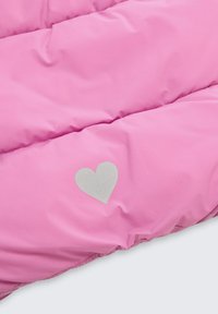 Weich gepolsterter rosa Stoff mit einem kleinen reflektierenden Herzsymbol nahe der unteren rechten Ecke.