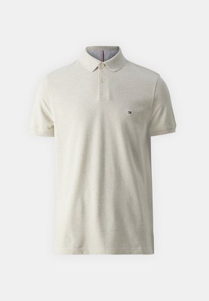 Jasno-beżowa koszulka polo z dwoma guzikami, krótkimi rękawami i subtelnym logo na piersi. Wnętrze kołnierza posiada wzór w paski.