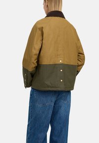 Jacket w kolorze oliwkowym i brązowym, w blokach kolorystycznych, z kołnierzem w korduroy, zatrzaskami i luźnym krojem, wykonany z lekkiego materiału.