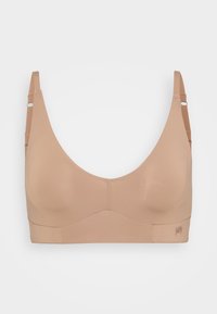 Wireless bra in nude color, made of smooth fabric. Features wide straps, a seamless design, and a subtle logo on the band.