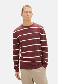 Bordeaux pullover trui met witte horizontale strepen, ronde hals, zachte textuur en ribgebreide boorden en zoom, gedragen met beige shorts.