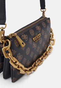 Mustavärinen tekokuitulaukku, jossa on kultaketju, vetoketjusuljenta ja logotyyppitys. Materiaalissa on monogrammikuosi.