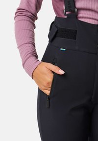Zwarte outdoorbroek met een ritszak, verstelbare banden en klittenbandsluiting. Het materiaal lijkt glad met een slim fit.