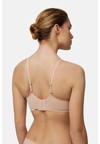 Sujetador en beige claro, diseño sin costuras, con tirantes ajustables, que cuenta con un cierre de gancho y ojo en la parte posterior, fabricado con tejido suave.
