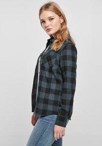 Schwarz und türkis kariertes Hemd mit Button-down-Kragen, Brusttaschen und langen Ärmeln. Hergestellt aus gewebtem Stoff, der eine strukturierte Passform zeigt.