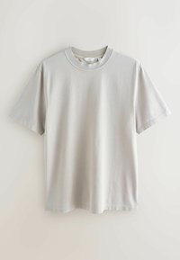 T-shirt en coton gris clair avec col rond, manches courtes et coupe décontractée. Le tissu a une texture lisse et douce, sans motifs.