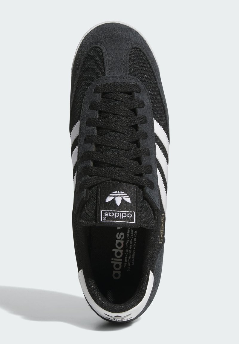 Schwarzer Adidas-Sneaker mit weißen Streifen, schwarzen Schnürsenkeln und Logo auf der Zunge und Ferse, von oben auf weißem Hintergrund gezeigt.