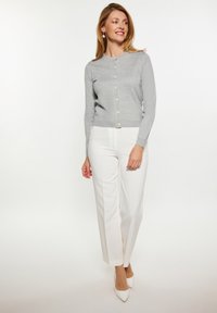 Cardigan tricotat gri, cu mâneci lungi și decolteu rotund, având butoane acoperite cu țesătură. Asortat cu pantaloni albi straight-leg și tocuri.