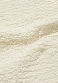 Tessuto strutturato di colore bianco sporco, caratterizzato da un motivo stropicciato. Materiale morbido e leggero con una finitura leggermente opaca.