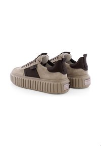 Baskets en suède beige avec des accents marron foncé, semelle plateforme texturée et cols rembourrés. Présente un détail de logo près du talon.
