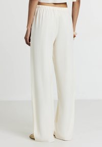 Pantaloni a gamba larga in morbido tessuto a crema testurizzato con vita elasticizzata, caratterizzati da una finitura liscia e un fit rilassato.