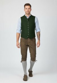 Zelená vlněná vesta se stříbrnými knoflíky a dvěma kapsami, v kombinaci s hnědými lederhosen, šedými podkolenkami do délky kolen a hnědými botami. Ležérní střih.