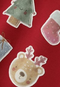 Tessuto rosso con design in applicazione, tra cui un albero di Natale verde sorridente, una calza rosa, un regalo blu e un orso con corna.