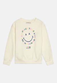 Kremfarget hettegenser med en sirkulær grafikk som viser et smilende ansikt og fargerik tekst som står: "Vi er det nye samfunnet." Ribbestrikkede mansjetter.