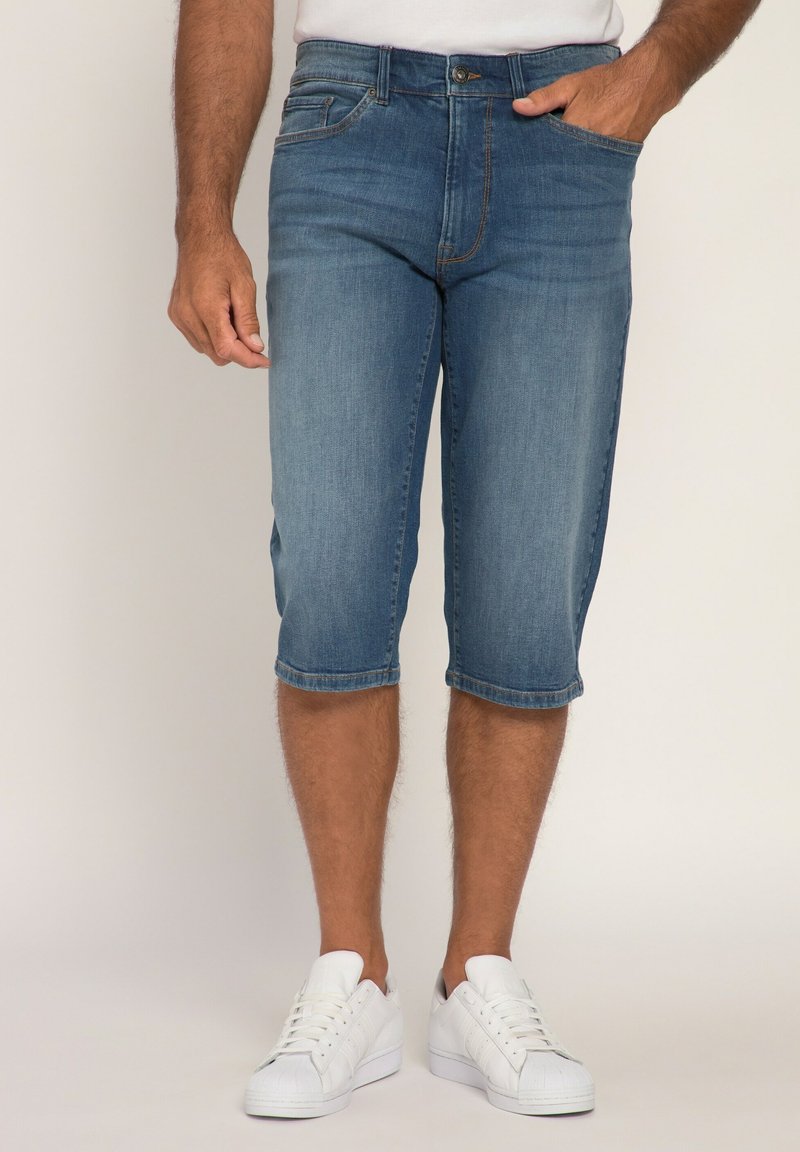 Denimshorts i ljusblått, knälånga, med rak passform, fem fickor och dragkedja. Bärs med vita sneakers.