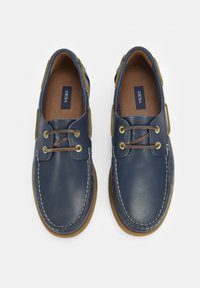 Marineblaue Lederschuhe für Boote mit braunen Schnürsenkeln und dekorativen Nähten. Gummisohlen mit beigefarbenen Akzenten. Das Innere ist mit einem braunen Futter ausgestattet.
