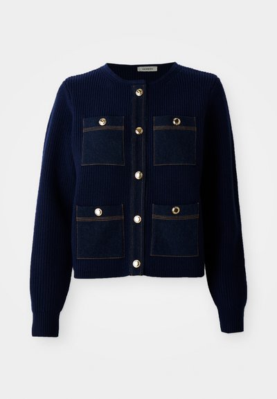 Marineblaue Rippstrick-Cardigan mit vier Fronttaschen. Verfügt über kontrastierende Denim-Taschenpaneele und goldfarbene Knöpfe. Rundhalsausschnitt, lockere Passform.