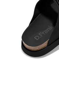 Sandalia negra con suela de corcho, que presenta un diseño de tira ancha y el texto "D.Franklin" en la plantilla. Textura suave y estilo minimalista.