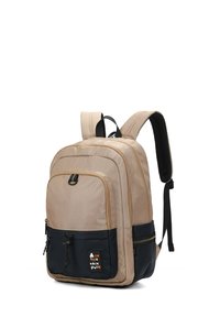 Zaino beige e nero con spallacci imbottiti, tasche con zip e texture liscia. Accenti di colore a contrasto e una patch con logo sul fronte.