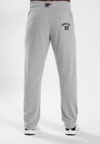 Grijze sweatpants met een elastische tailleband, voorzien van twee achterzakken en de tekst "Gorilla Mr. 82" gedrukt boven de rechterzak.