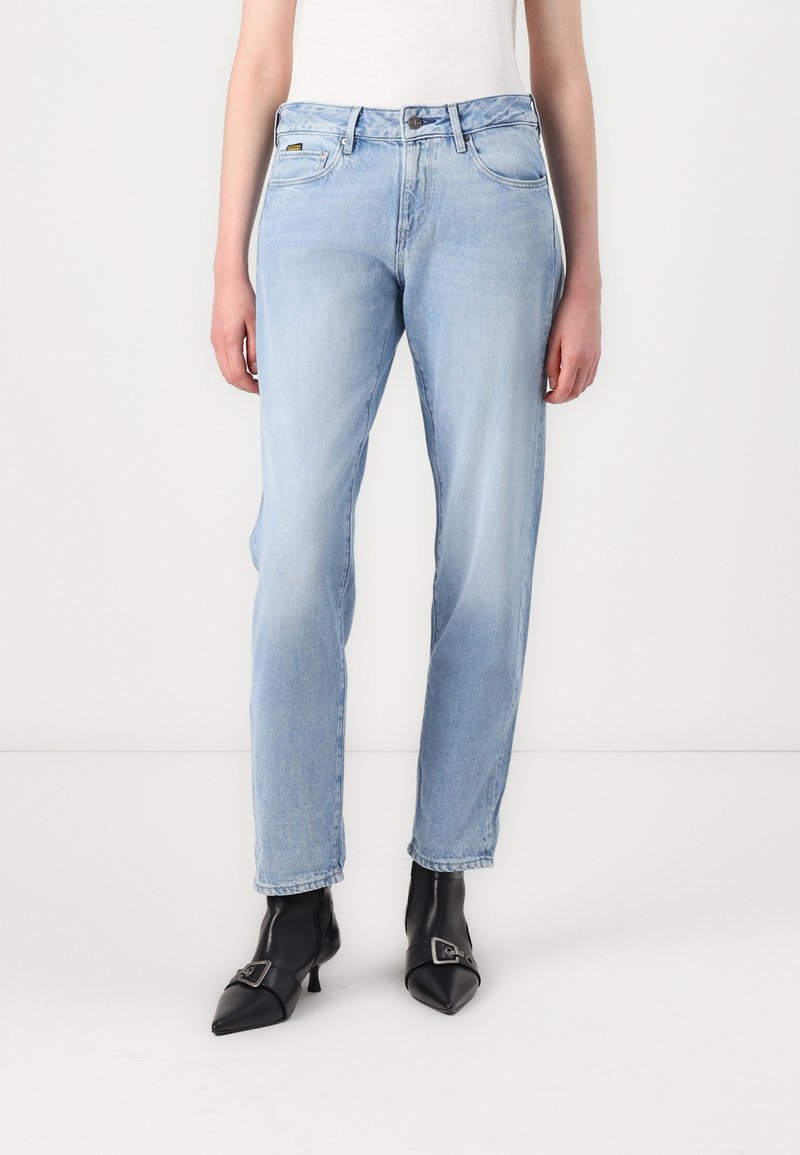 Lichtblauwe denim jeans met een rechte pasvorm, met een middelhoge taille, voorzakken en een versleten afwerking. Gekleed met zwart leren hakken.