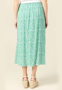 Groene midi-rok met een wit abstract patroon, gemaakt van lichte stof. Heeft een elastische tailleband en een vloeiende silhouet.