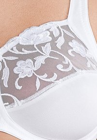 Witte bh met een bloemenkant overlay met ingewikkelde borduursels. De cups zijn soepel ontworpen met een zachte textuur en brede schouderbanden.