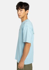 Light blue short-sleeve t-shirt made from cotton with a relaxed fit. It features a graphic design on the front and left sleeve.