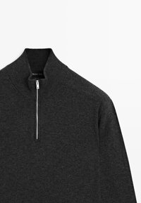 Dunkelgrauer Wollpullover mit einem kurzen silbernen Reißverschluss und einem gerippten hohen Kragen, flach auf einem weißen Hintergrund ausgelegt.