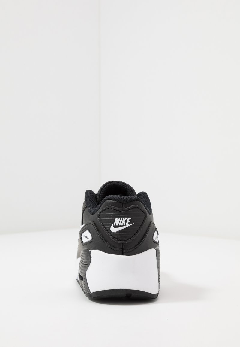 Schwarzer und weißer Nike-Sneaker mit strukturiertem Obermaterial, gepolstertem Schuhkragen und auffälligem Logo an der Ferse, sowie einem charakteristischen Air-Sohlen-Design.