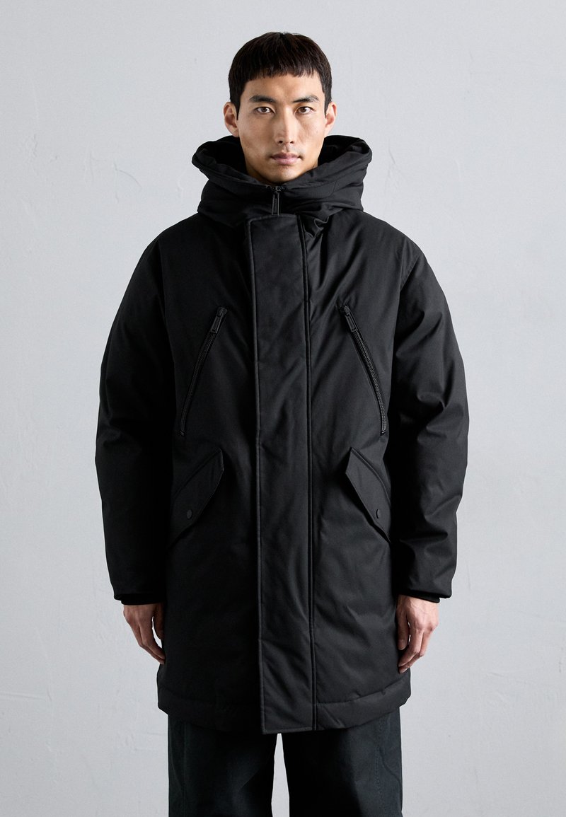 Schwarze gepolsterte Parkajacke mit hochgeschlossenem Kragen, mit Reißverschlüssen versehenen Taschen und einer enganliegenden Kapuze. Sie zeichnet sich durch eine glatte Textur und einen geraden Schnitt aus.