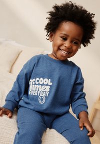 Survêtement en coton bleu avec col rond, manches longues et texte imprimé blanc "COOL Times EVERYDAY" accompagné d'un smiley.