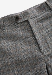 Gray plaid trousers featuring a woven texture, with brown accents and a single black button at the waistband. Classic fit design.