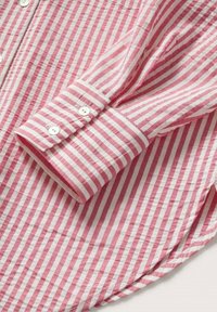 Poignet de chemise à manches longues à rayures verticales rouges et blanches avec boutons blancs et patte de boutonnage, posé à plat.